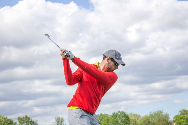 man in red shirt swinging golf